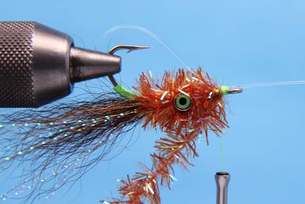6. Pull the monofilament down, leaving roughly a 1/4 inch gap between the bottom of the hook and the monofilament weed-guard. Tie the monofilament in place and cover it with 2 turns of Crystal Chenille. 