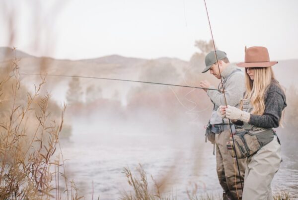 A couple fishing on a riverbank, tying the flys to the hooks for flyfishing.