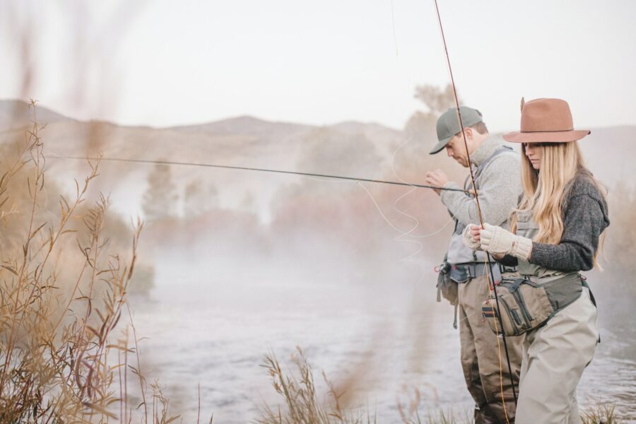 A couple fishing on a riverbank, tying the flys to the hooks for flyfishing.