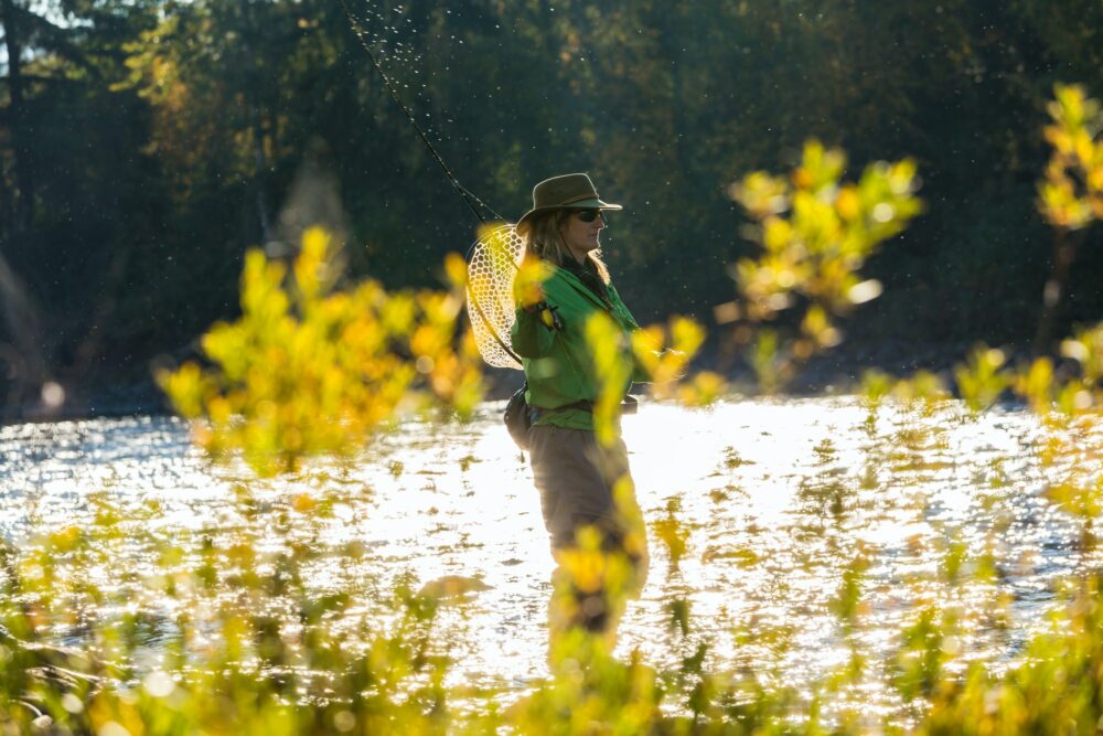 Fly fisherwoman casting & fishing on river, British Colombia, Canada.