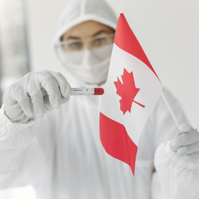 The scientist in coverall suit with a coronavirus sample and Canadian flag