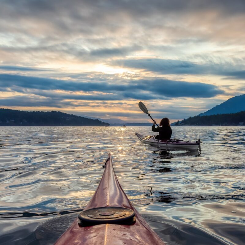 Adventurous Woman on Sea Kayak paddling in the Pacific Ocean