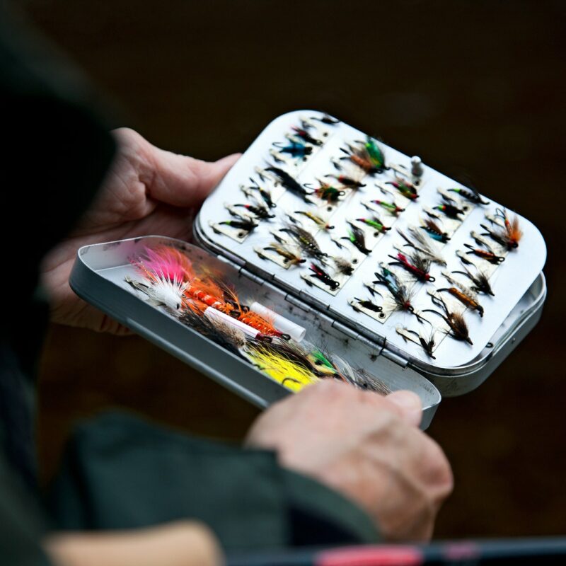 Person holding fly fishing lures, close up