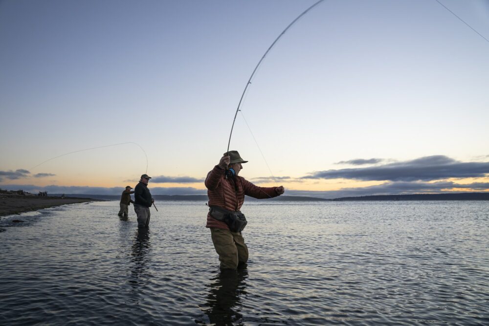 Two fly fishermen cast for searun coastal cutthroat trout and salmon with their guide standing