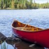 Red wooden canoe on the shore of a Boundary Waters lake on a bright autumn day