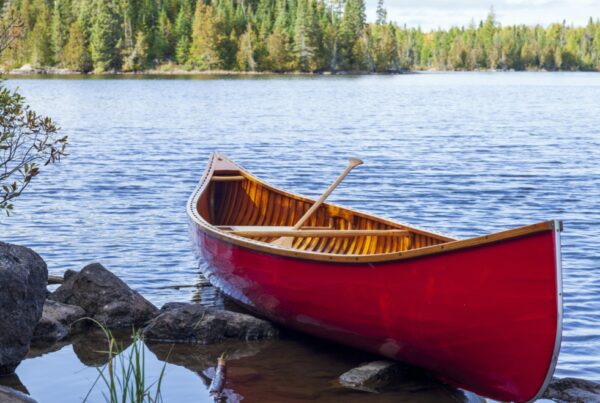 Red wooden canoe on the shore of a Boundary Waters lake on a bright autumn day