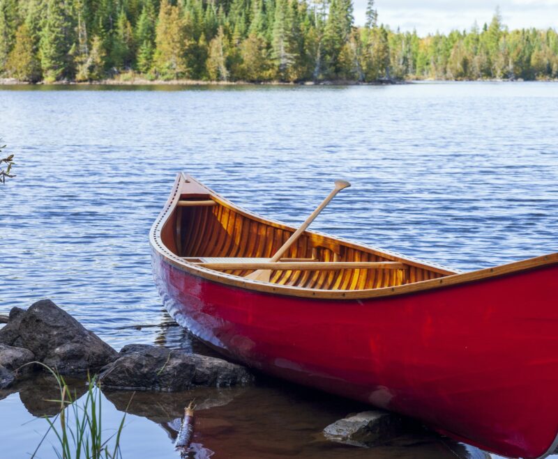 Red wooden canoe on the shore of a Boundary Waters lake on a bright autumn day