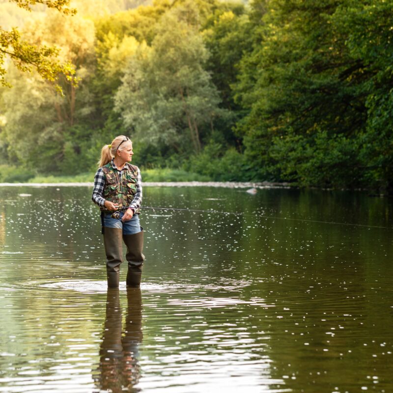 Beautiful girl spinning fishing in the river